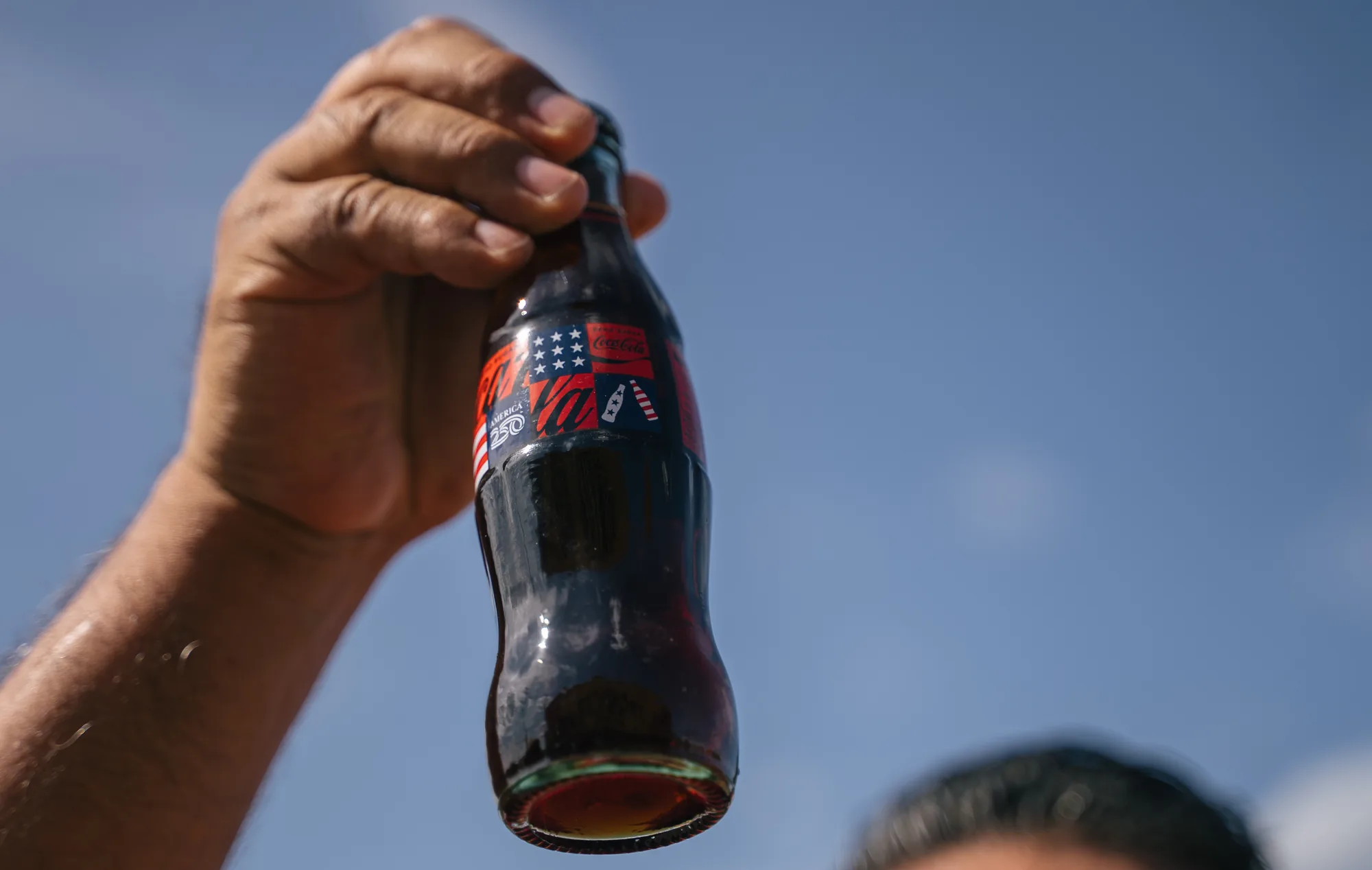 Commemorative Coca-Cola bottle held up at the Frontier Spirit mural unveiling in Abilene, Texas