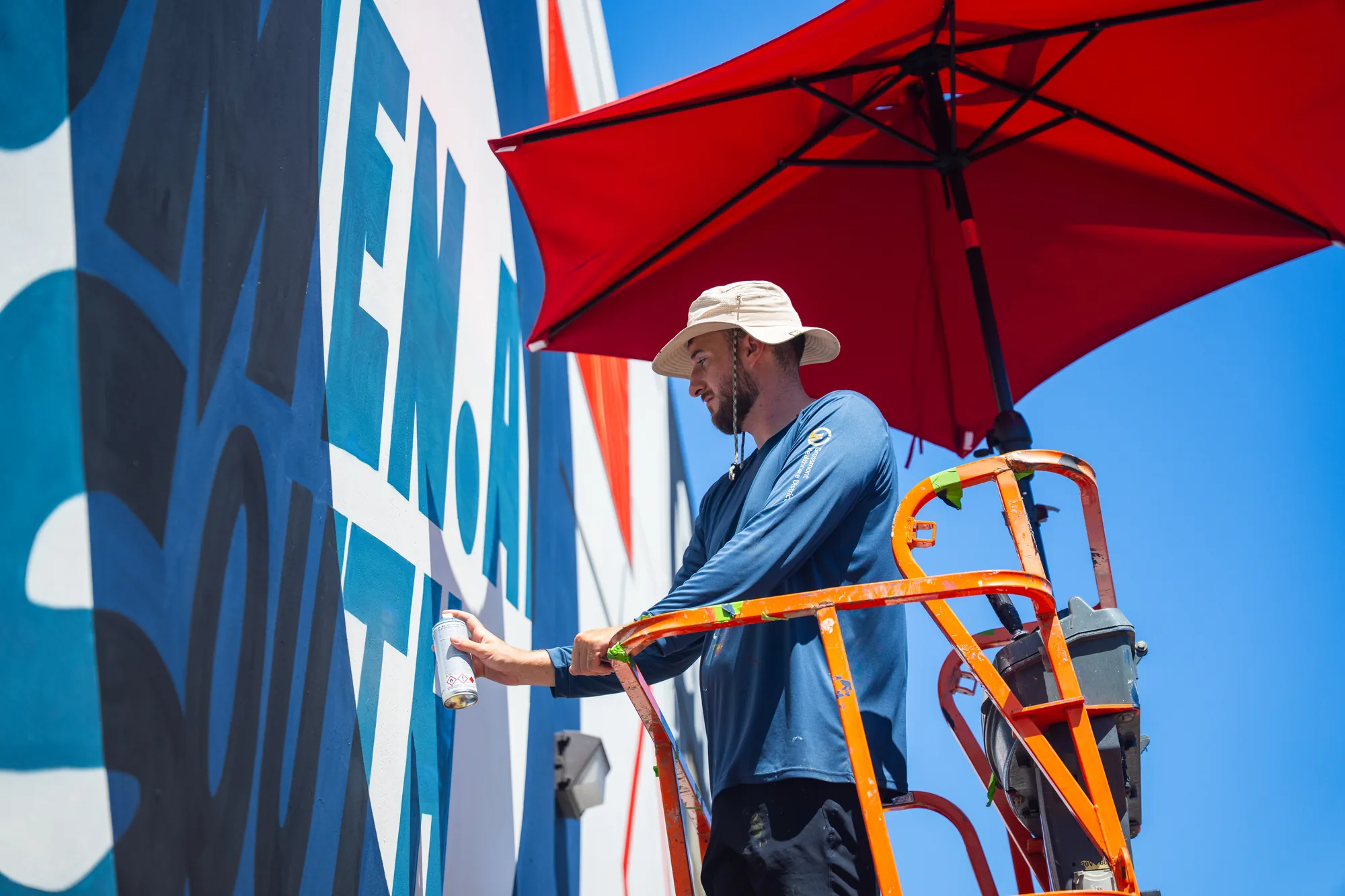 Pezer97 painting the Omen AI building mural from a boom lift, 2026